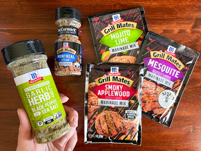 Two bottles and three packets of McCormick seasoning on a wood table top.