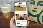 a hand holding an iphone with the starbucks app 