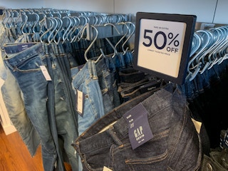 A row of mens demin jeans bellow a sign that say 50% off.