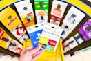 hand holding gift cards in front of gift card display