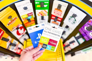 hand holding gift cards in front of gift card display