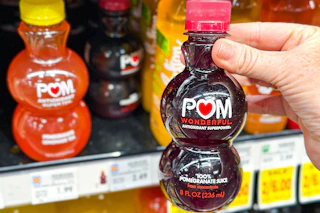 hand holding a bottle of pom juice