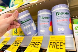 person grabbing a bottle of bloom supplements off a shelf with buy one get one free tags