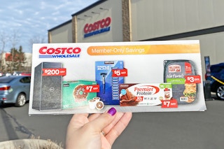 someone holding up a costco ad with savings outside of a costco