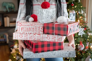 woman holds arm full of christmas presents