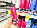hand holding up a hydro flask water bottle in front of a clearance display