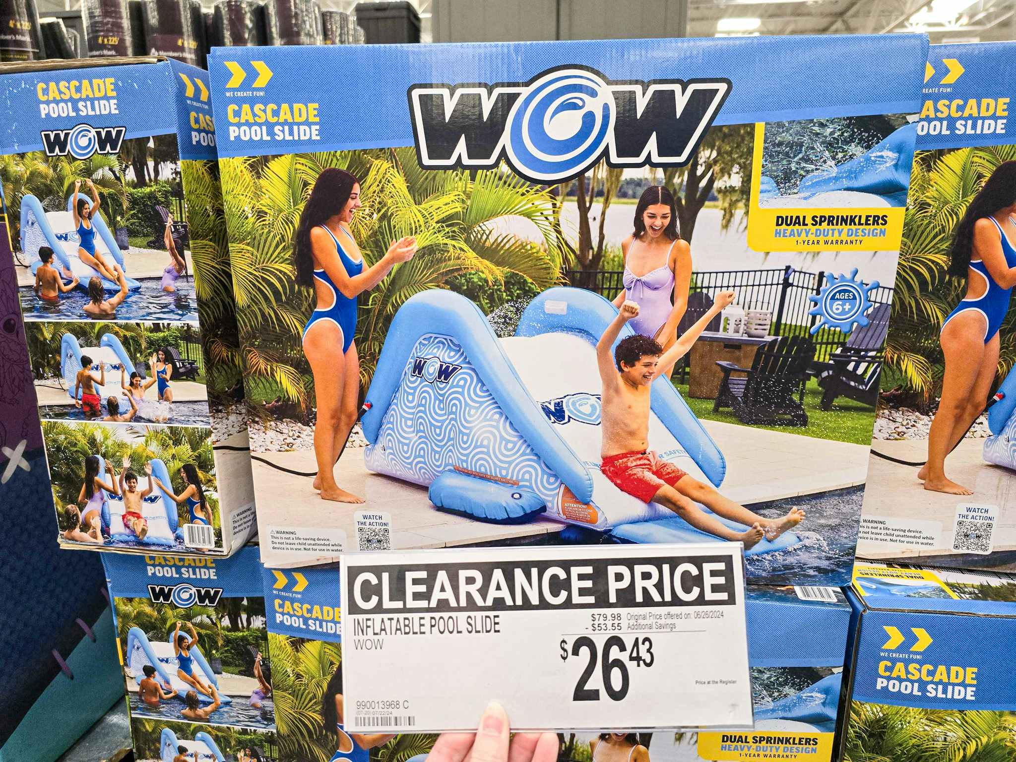 person holding a clearance sign for $26.43 in front of a water slide