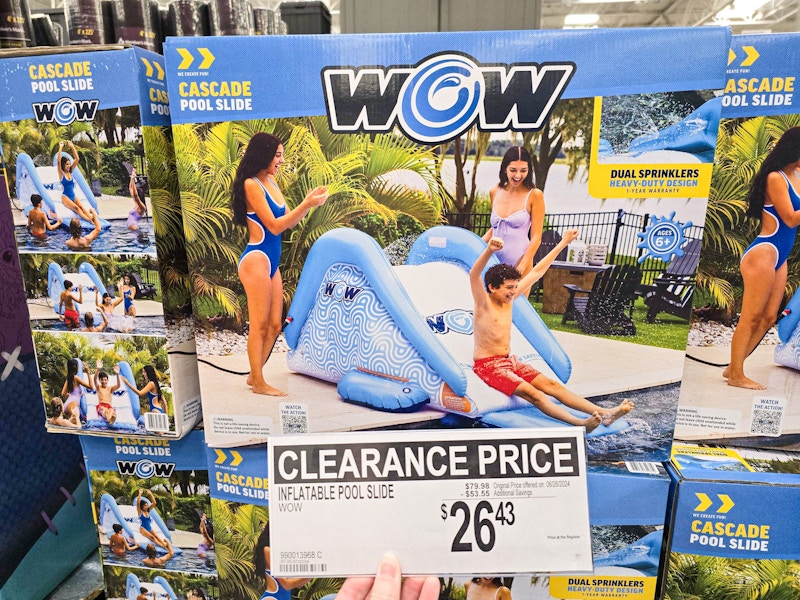 person holding a clearance sign for $26.43 in front of a water slide