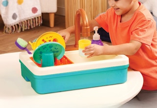 child playing with the plastic white and teal immersive sink