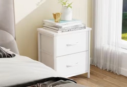 white 2-drawer night stand next to a window and bed