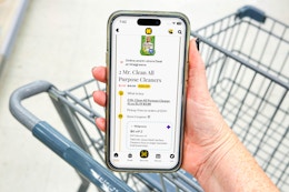 hand holding smartphone over shopping cart with kcl app and 1-clip coupon deal