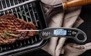 a meat thermometer on a steak on a grill