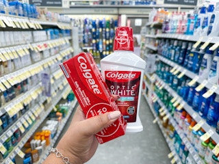 hand holding colgate toothpaste and mouthwash at walgreens