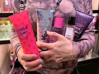 Woman with arms full of lotions, and fragrance beauty items.