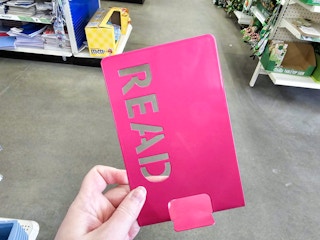 person holding a pink book end with "read" on it