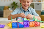 child playing with magnetic building blocks at table