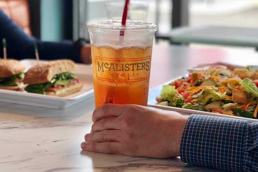 Two people sitting at a table eating food at a McAlister's deli restaurant