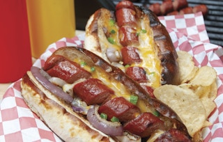 two hot dogs that were cut into a spiral in a bun with toppings