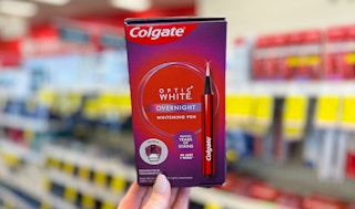 a hand hold a box with a teeth whitening pen