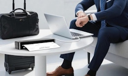 a person on a laptop at a table with a portable printer