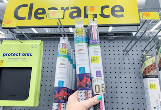 cricut vinyl tubes hanging on clearance hooks with clearance sign in background