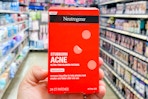 a hand holding a red pack of pimple patches in a store aisle