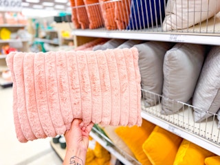 hand holding a throw pillow in front of a target shelf