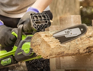 a green chainsaw sawing wood