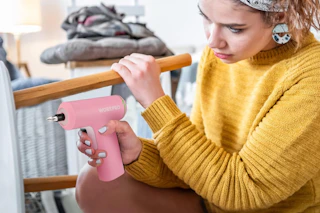 woman using screwdriver to assemble furniture