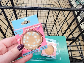 hand holding a bronzer with another in a cart