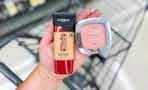 person holding maybelline foundation and blush over a cart