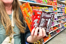 hand holding packs of Hershey's, Reese's and Kit Kat Candy Bars