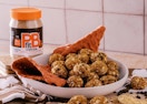 a canister of peanut butter powder next to a bowl of peanut butter snack balls