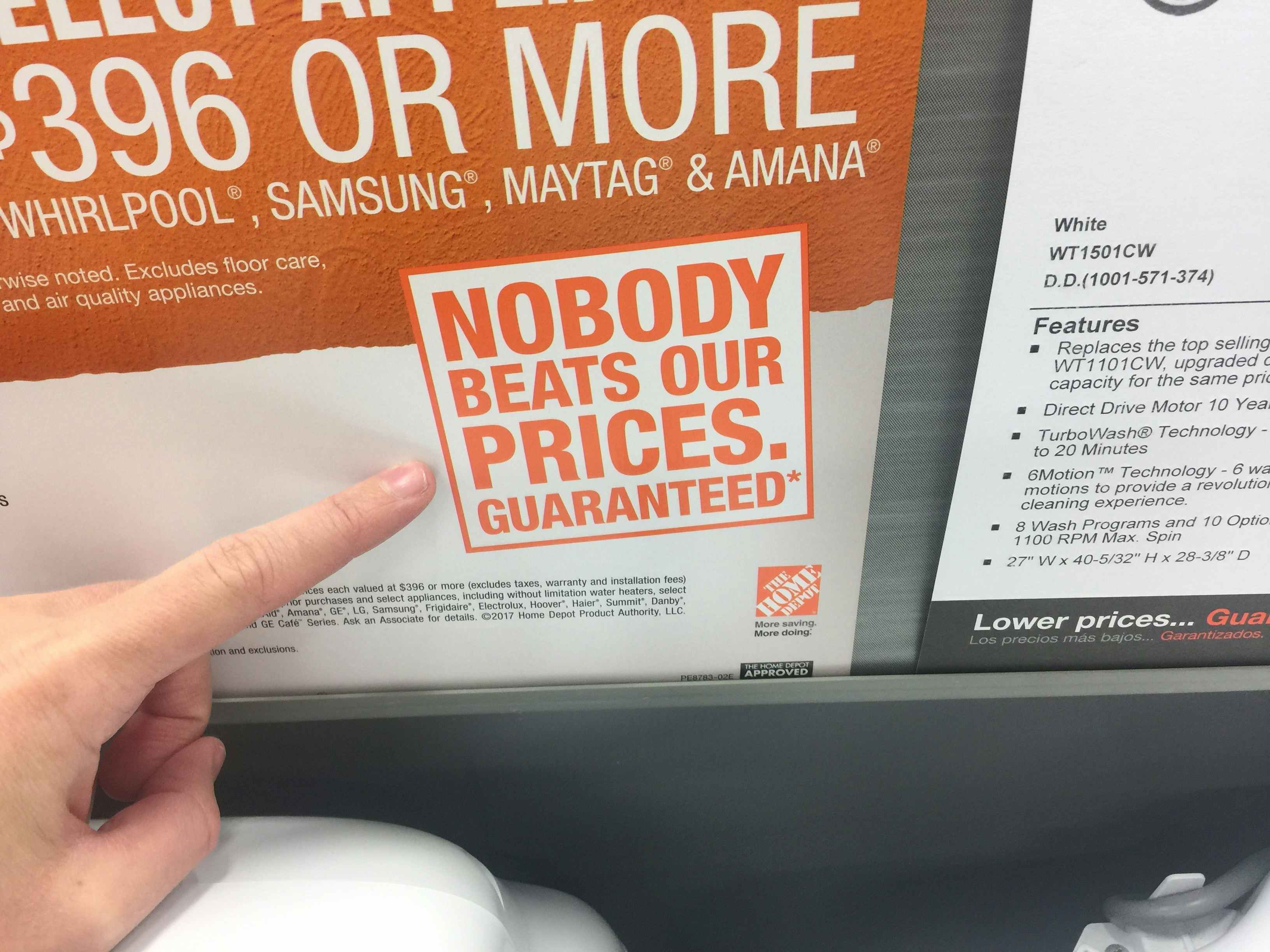 A person pointing to the graphic that reads, "Nobody beats our prices. Guaranteed*" next to the Home Depot price match policy on the wall...
