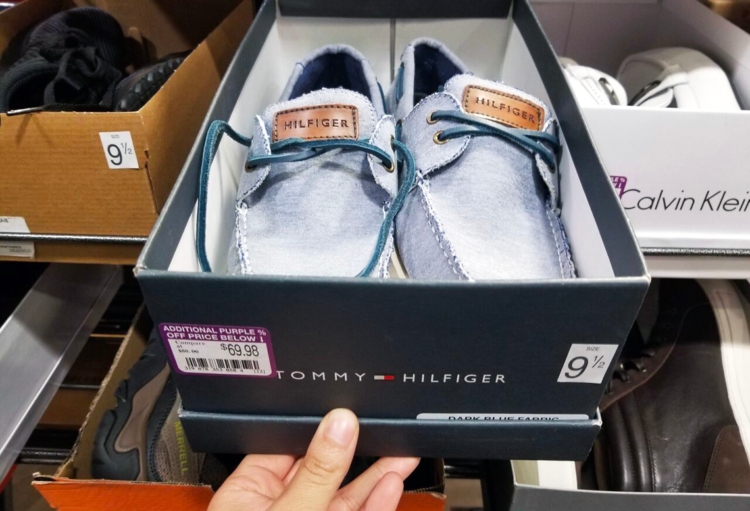 Person pulling out a box of Hilfiger shoes from a DSW rack