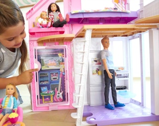 lifestyle photo of a child playing with the Barbie Malibu House and her Barbie dolls