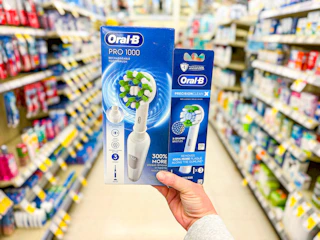 hand holding oral-b pro 1000 toothbrush and brush refills in walgreens