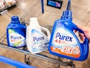 hand holding a bottle of purex detergent with two bottles in walmart cart