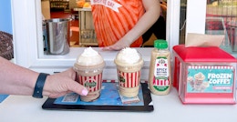 A Rita's employee serving some frozen coffees to customers