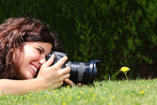 A woman snaps a photo of a flower with a camera
