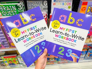 a person holding an ABC my first learn to write book in the children's book aisle at target
