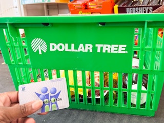 Person holding EBT card in front of a dollar tree cart