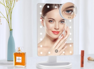 a lighted mirror on a vanity with perfume and lip gloss
