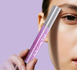 a person holding a tube of eyelash growth serum