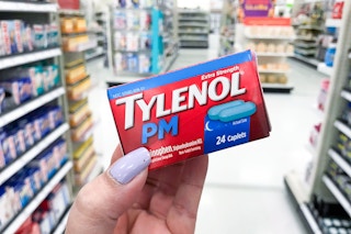 a hand holding a box of Tylenol in a store aisle