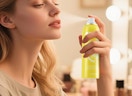 a person using a yellow can of makeup setting spray