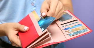 person taking credit card from pink wallet