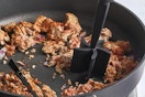 a meat chopper chopping meat in a pan 