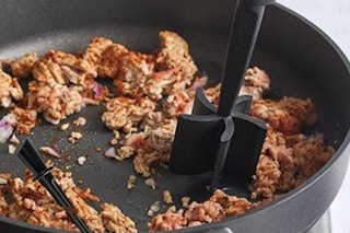 a meat chopper chopping meat in a pan