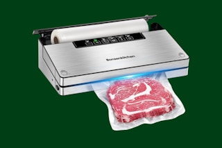 A vacuum sealer machine is sealing a piece of meat in a plastic bag.